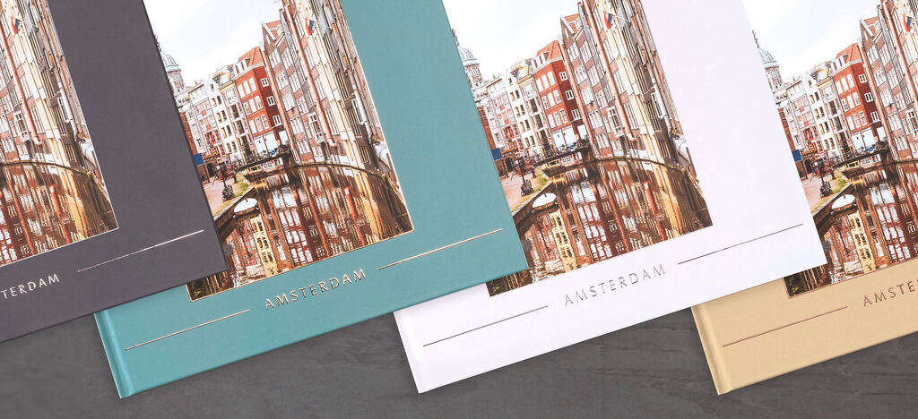 Tre olika färger av en CEWE fotobok visar en vy av byggnader i Amsterdam.