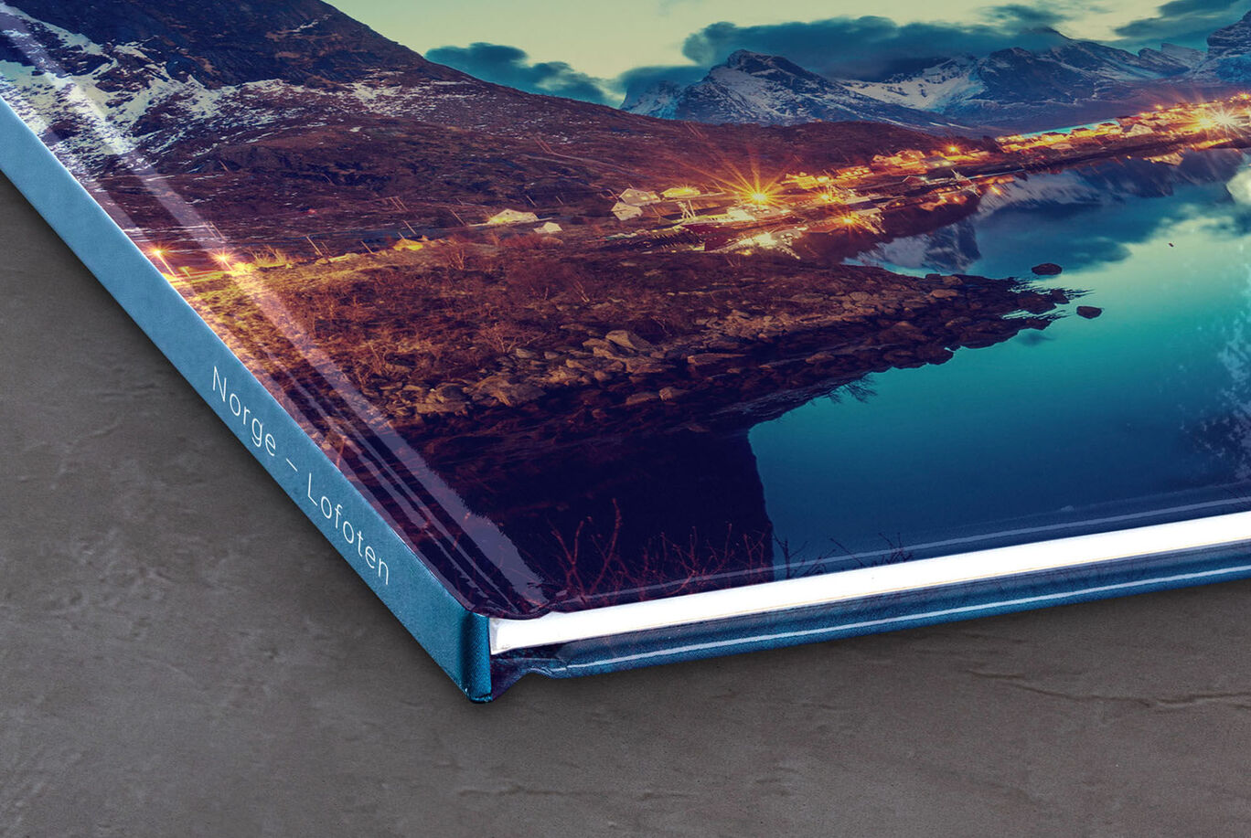 Detalj av ett CEWE fotoalbum som visar en vacker landskap. Det glänsande omslaget visar solnedgångens färger.